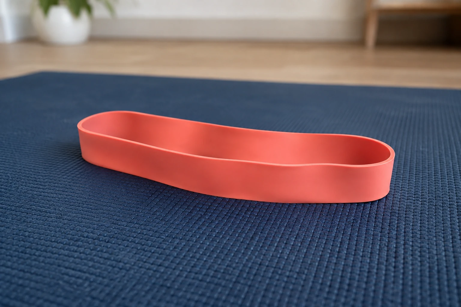 Bande élastique rouge posée sur un tapis de yoga bleu dans une pièce lumineuse